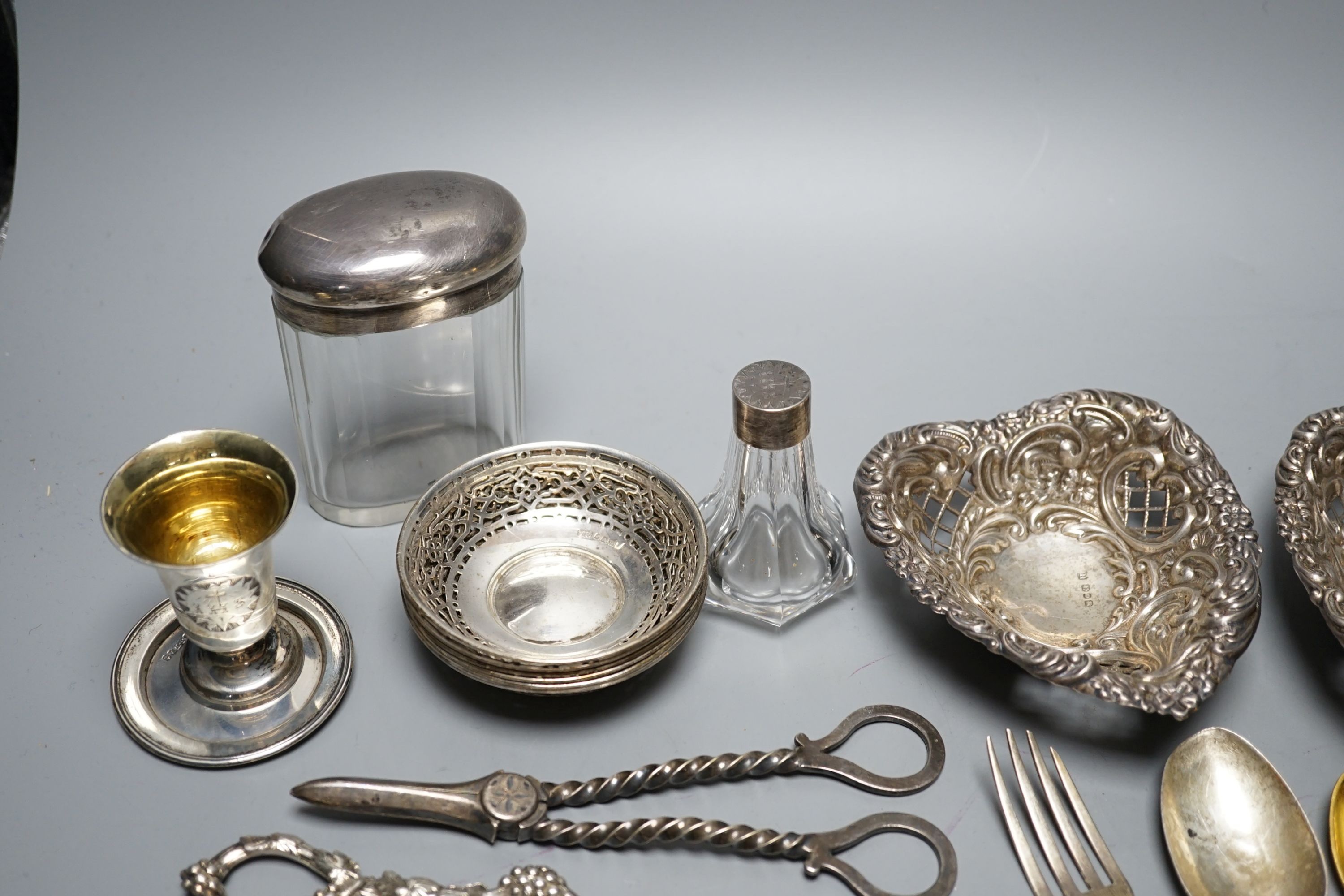 A cased Victorian silver part communion set, a silver cigarette case, two silver napkin rings, a set of five pierced silver bonbon dishes, a pair of Victorian silver grape shears, Georgian silver vinaigrette, pair of sil